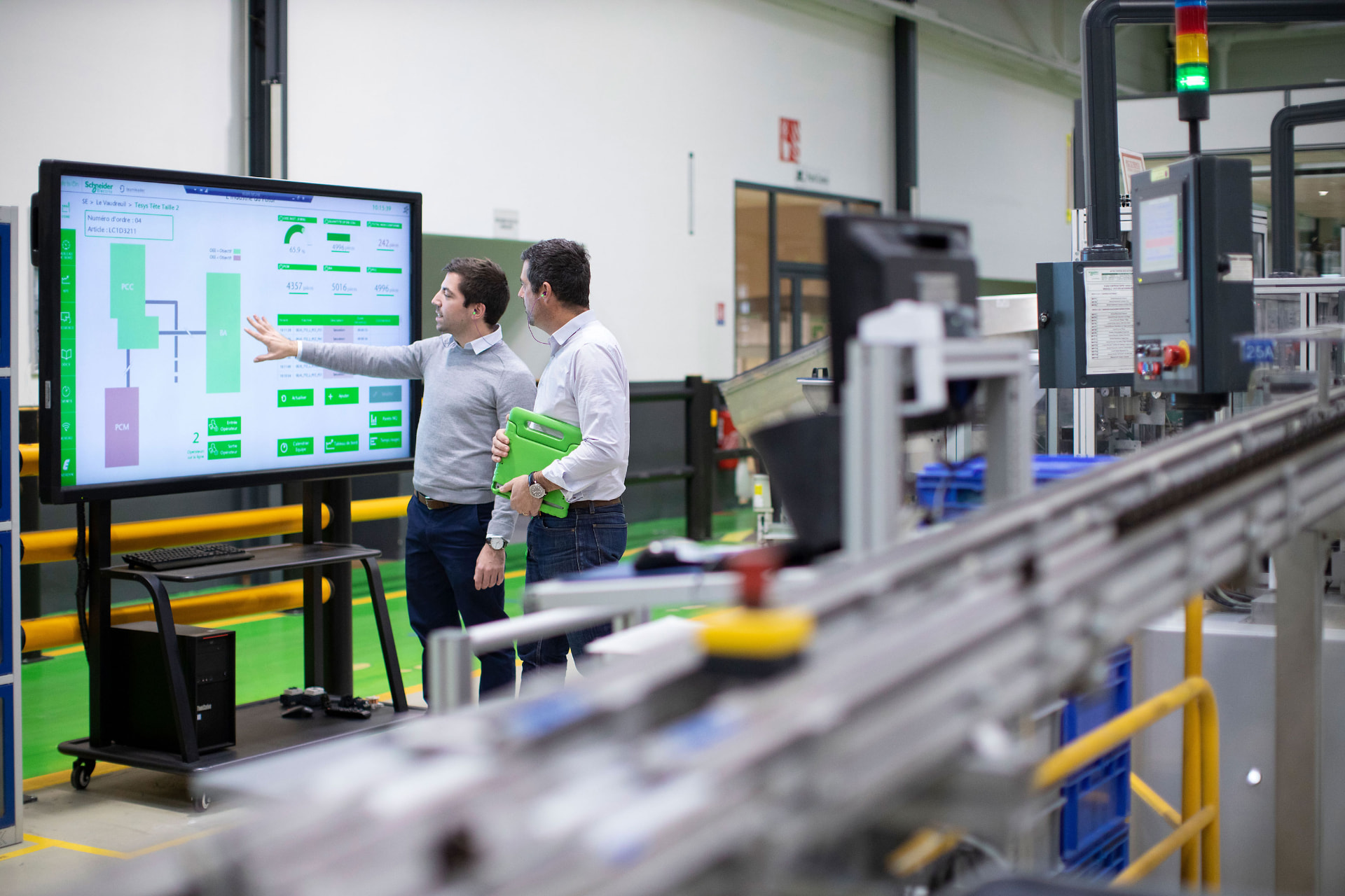 Engineers beside Schneider Electric industrial automation monitoring equipment
